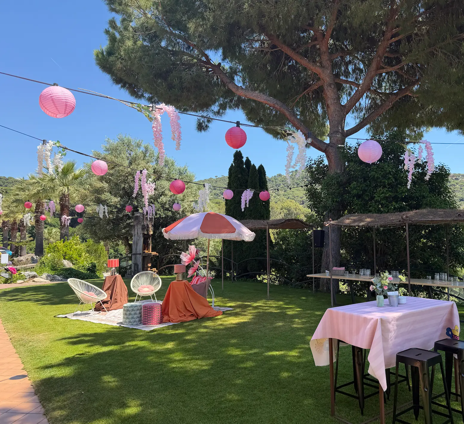 Pink lanterns and blossom garlands strung through the garden, with chill-out seating on the lawn
